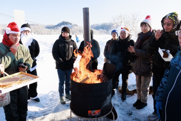 薪ストーブで暖をとる参加者